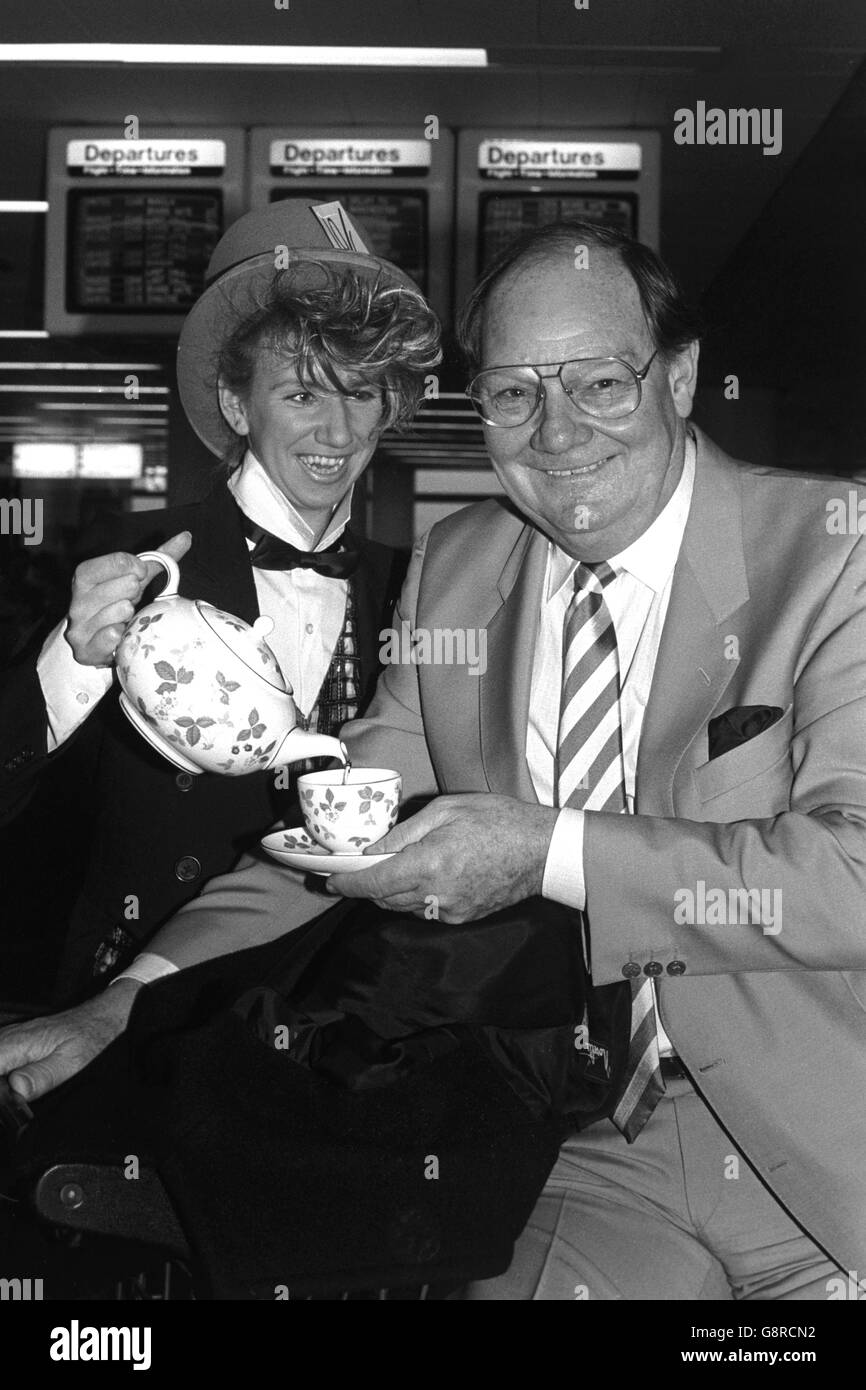 Television presenter Cliff Michelmore is poured a cuppa by 'Mad Hatter' Janine Webb, 24, a restaurant worker at Gatwick Airport, after presenting the 1987 Best Cup of Tea Awards to J. Lyons The Country Table at Gatwick. The award scheme aims to raise the standard of the service at Britain's airports. Stock Photo