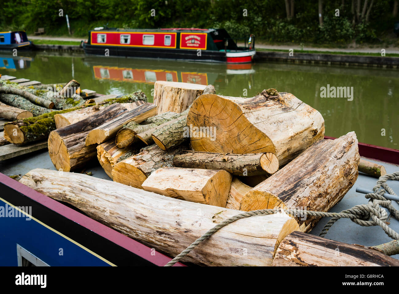 Sawn logs of wood on the roof of a narrow canal house boat Stock Photo