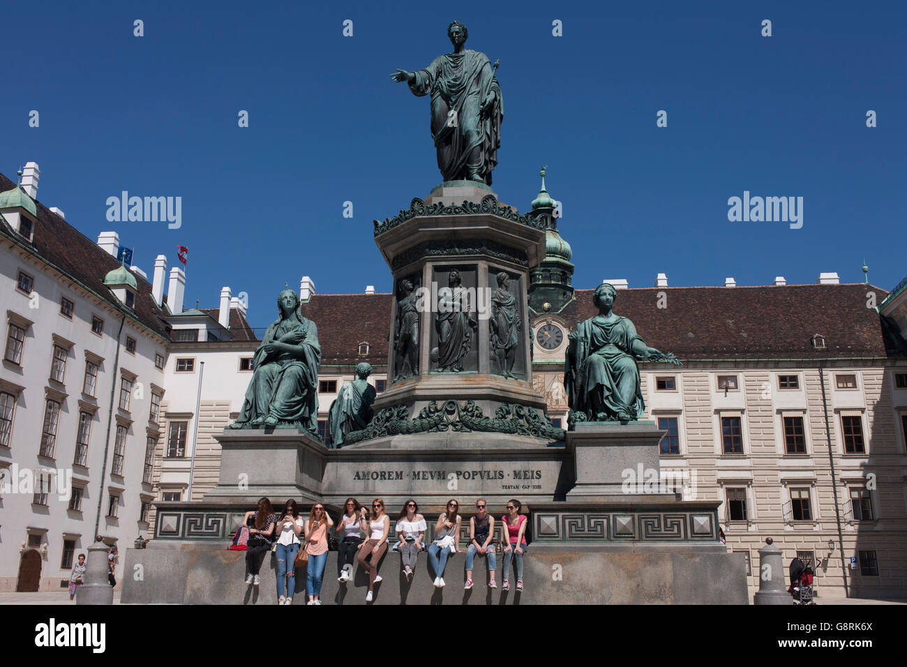 Young women sit beneath the monument to Emperor Franz Josef 2nd in the