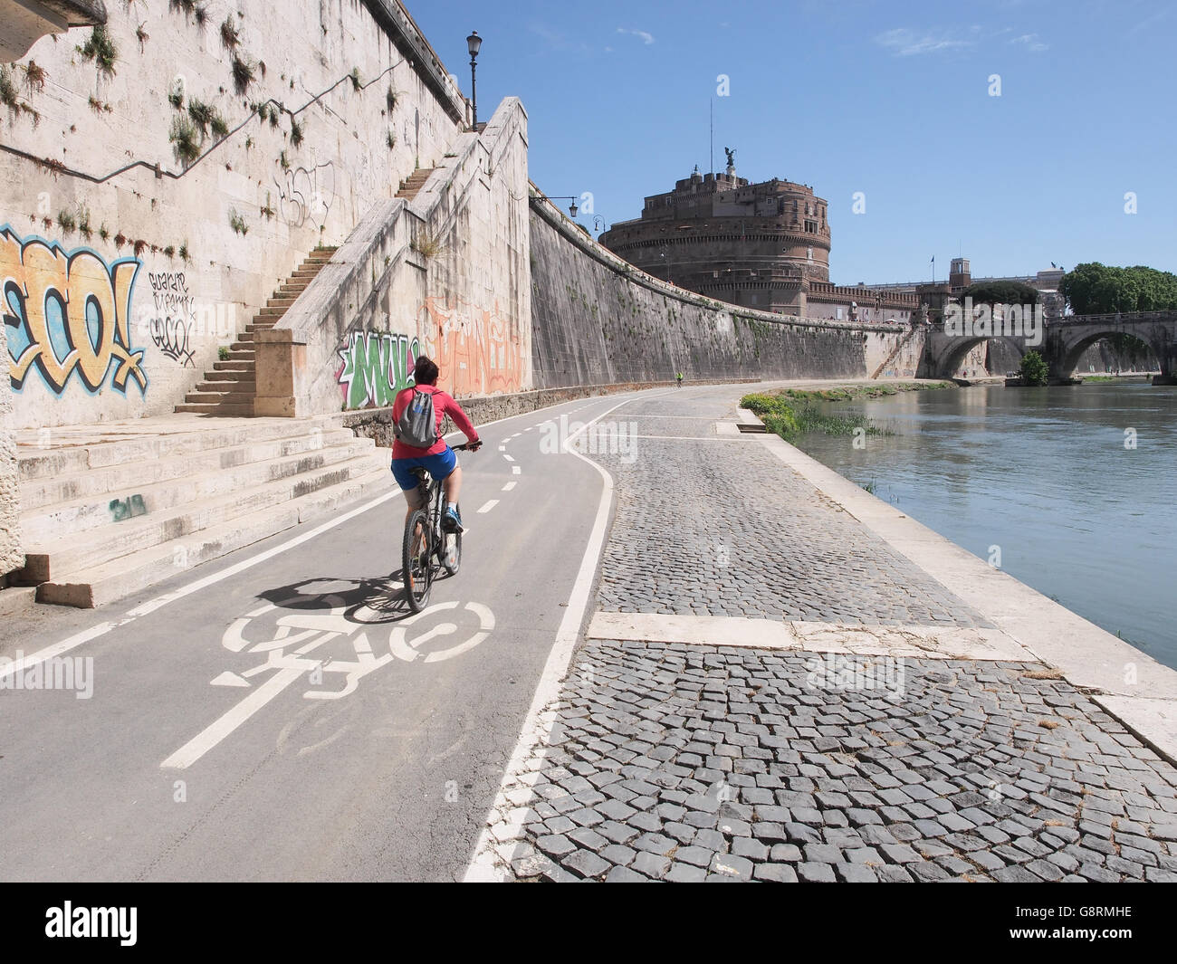Woman on cycle path near Tiber river with Castel Sant'Angelo in Rome ...