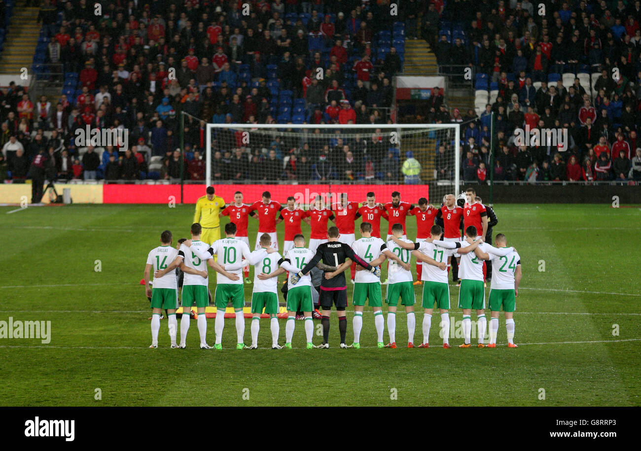 Wales' and Northern Ireland (backs to camera) pose for a minutes silence in memory of Belgium terror attacks during the International Friendly at the Cardiff City Stadium, Cardiff. Stock Photo