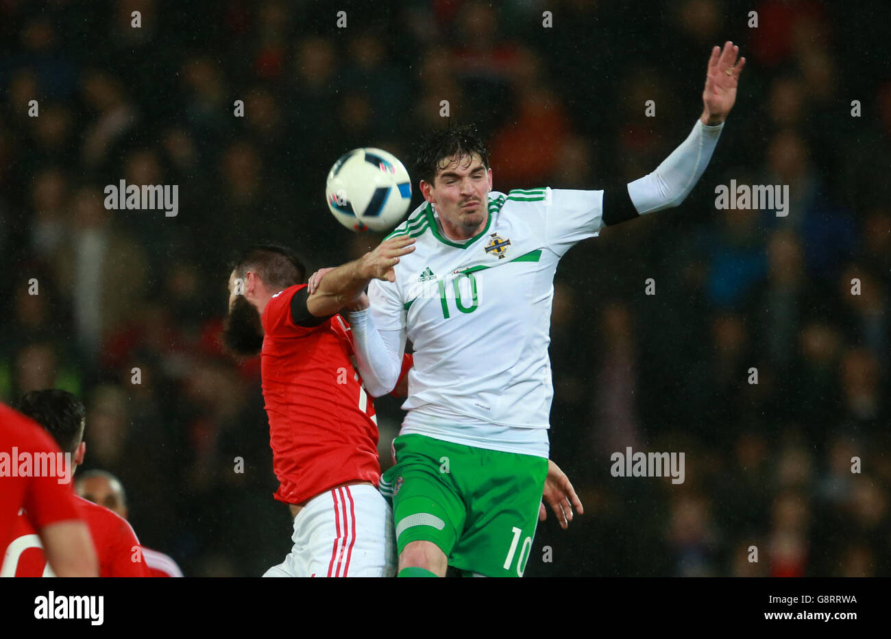 Northern Ireland's Kyle Lafferty (right) jumps highest to win the ball during the International Friendly at the Cardiff City Stadium, Cardiff. Stock Photo