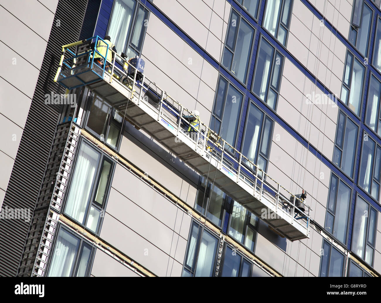 construction workers use suspended access platforms to install ceramic tiles to the facade of a new hotel in London, UK Stock Photo