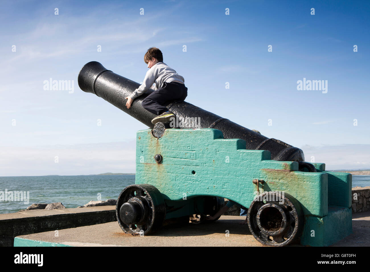 Ireland, Co Sligo, Strandhill, child playing on seafront cannon Stock Photo