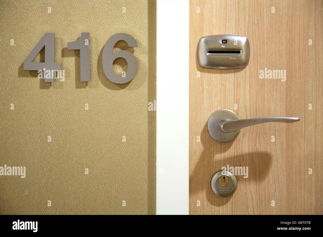 Close-up of a modern hotel door showing card-key operated access control next to metal room number sign Stock Photo