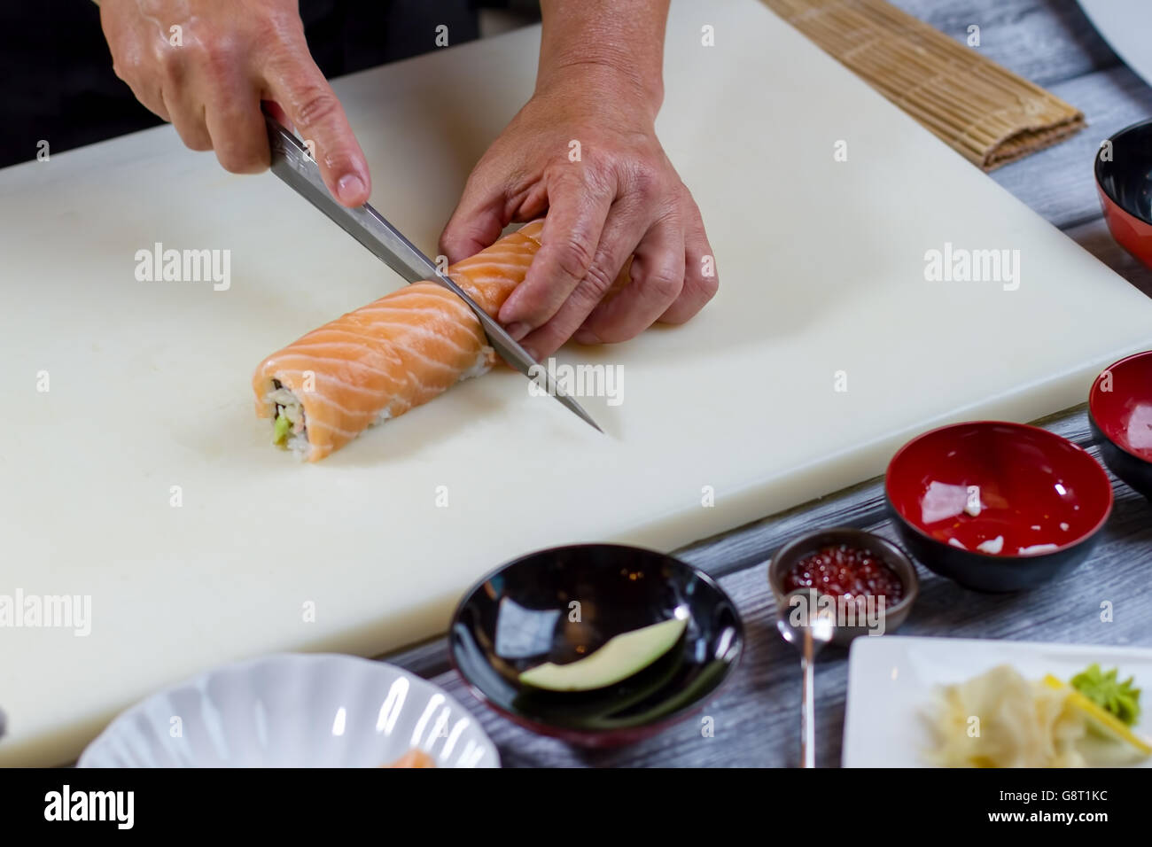 Hand holding knife cuts sushi Stock Photo Alamy