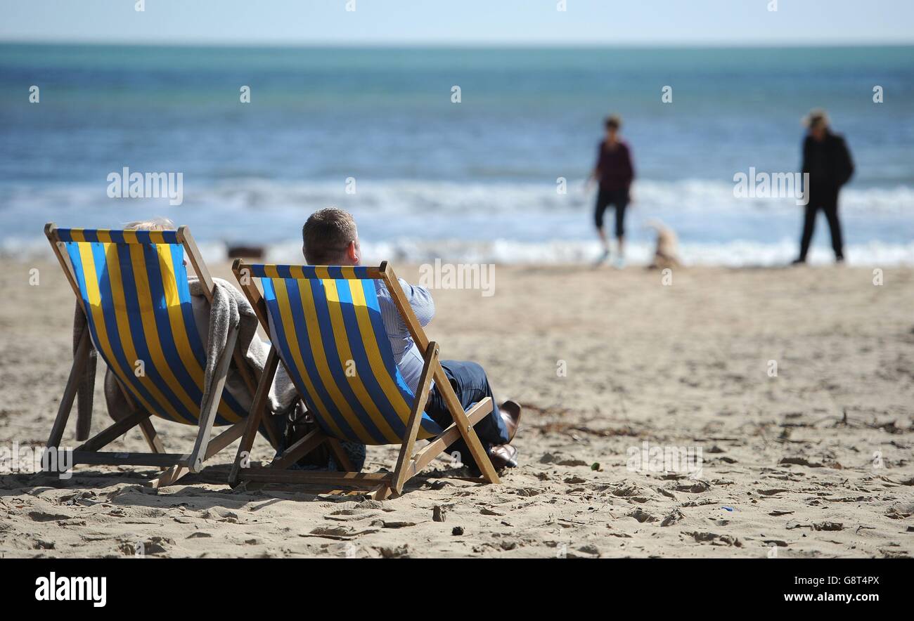 People enjoying the sun sitting in deckchairs on Bournemouth beach. Stock Photo