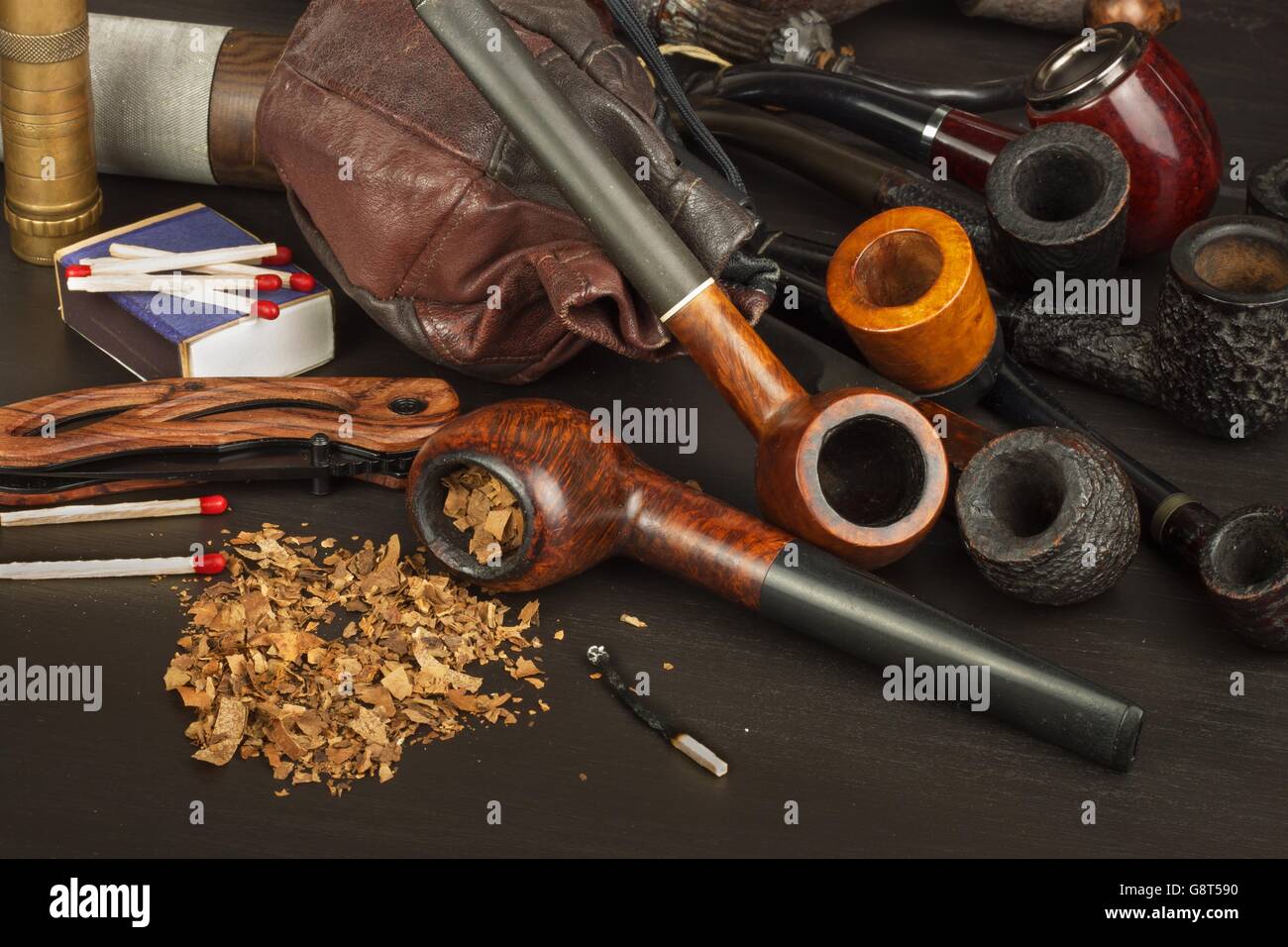 Wooden pipe with tobacco on a black background. Old tobacco pipe and  spilled tobacco Stock Photo