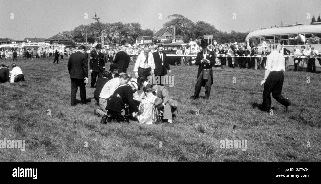 Police, ambulance men and other helpers encircle an injured jockey lying on the course after seven horses had fallen in a pile up near Tattenham Corner during the Derby at Epsom. Stock Photo