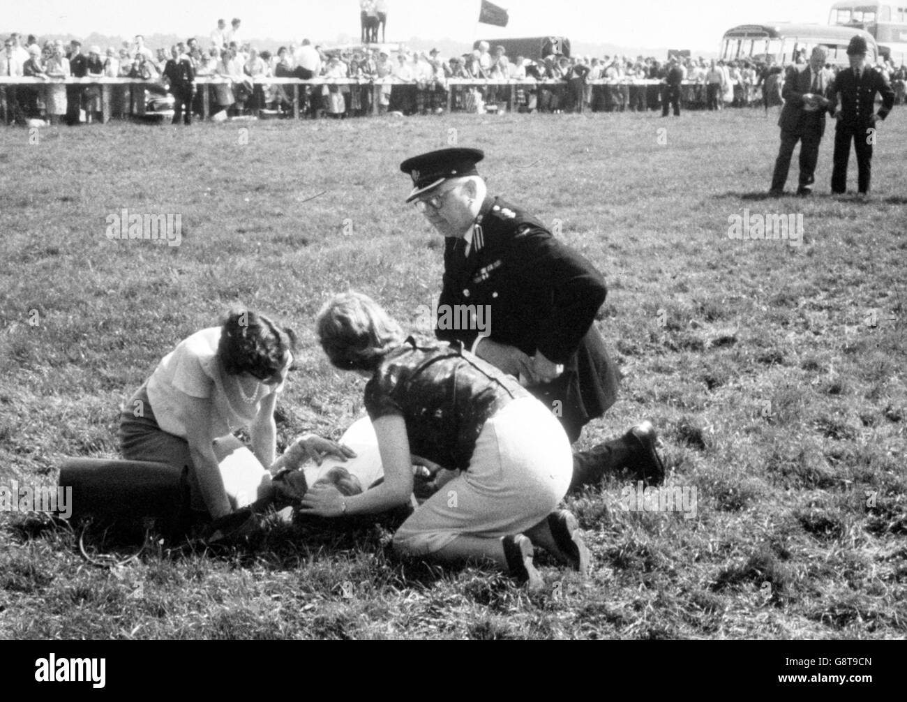 Police, ambulance men and other helpers encircle an injured jockey lying on the course after seven horses had fallen in a pile up near Tattenham Corner during the Derby at Epsom. Stock Photo