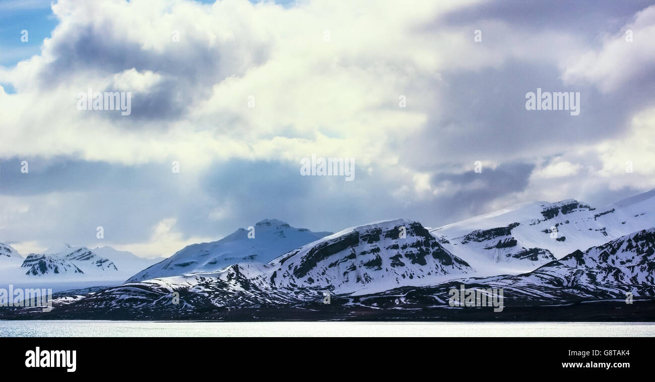Dramatic clouds over snowy mountains in the arctic Stock Photo
