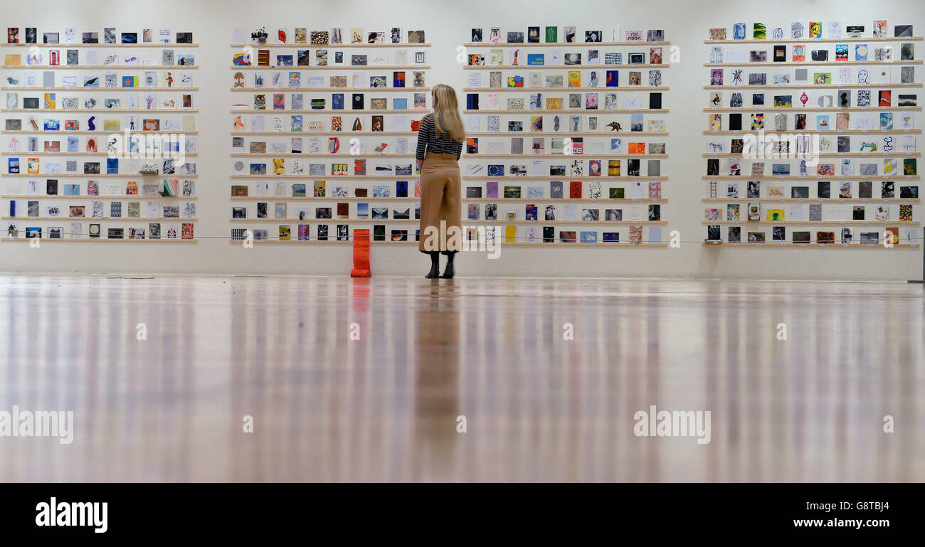 A gallery worker looks at postcards during the press preview for the