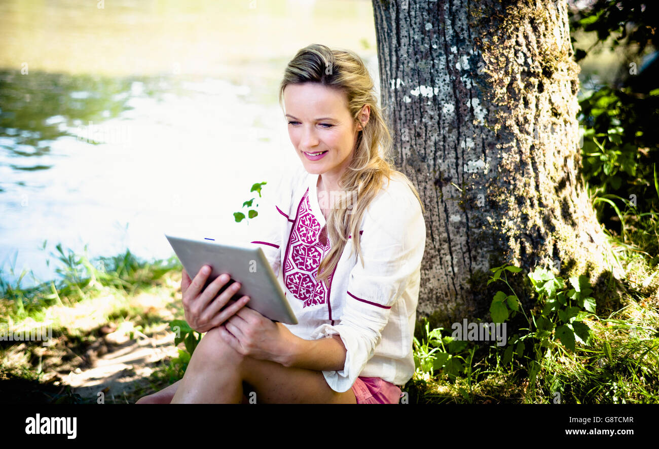 Young woman holding tablet PC outdoors, foothills of the Alps, Bavaria, Germany Stock Photo