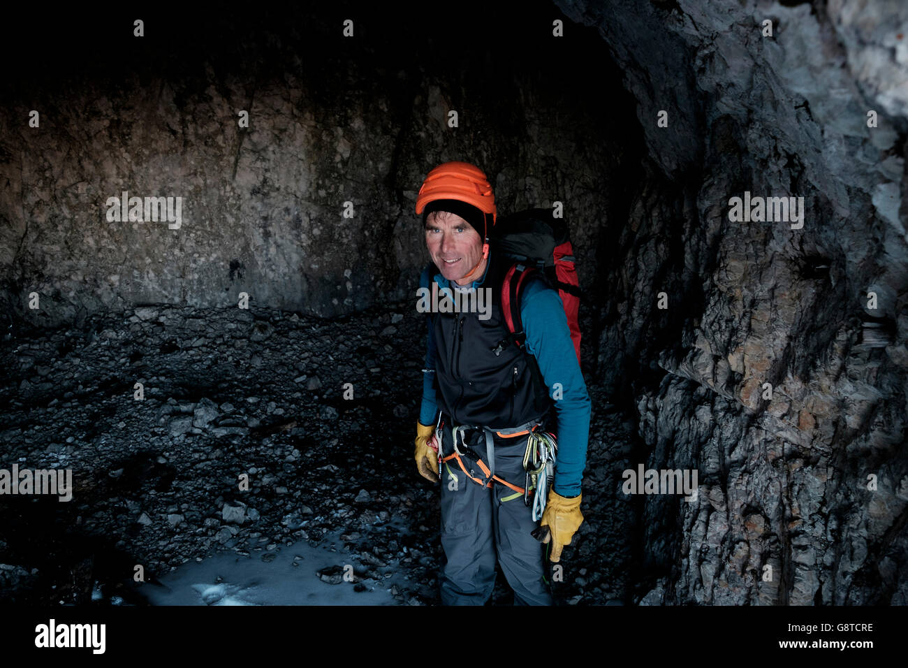 Mountain guide with helmet and backpack standing in cave Stock Photo