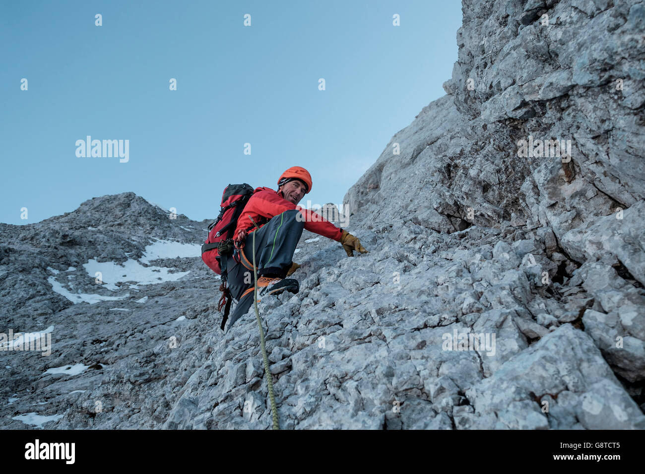 Mountaineer climbing steep wall in mountain range Stock Photo