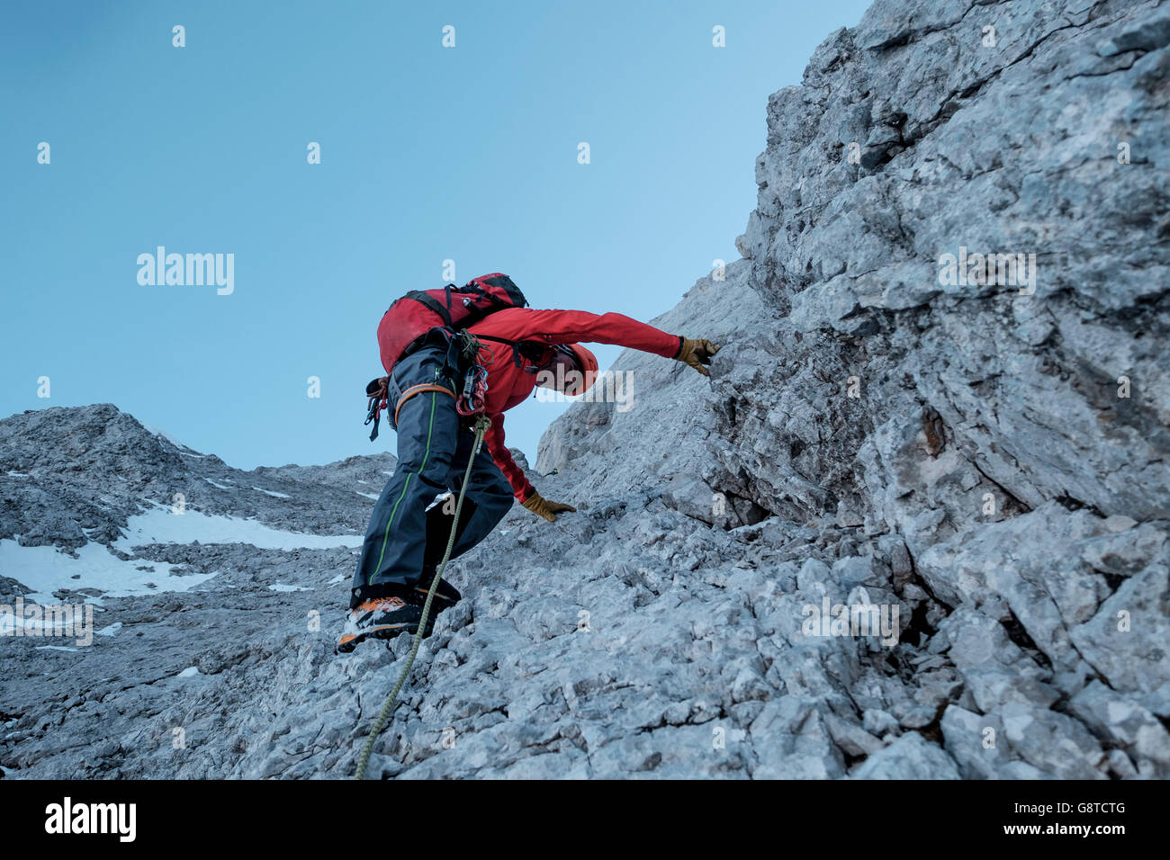 Mountaineer climbing steep wall in mountain range Stock Photo