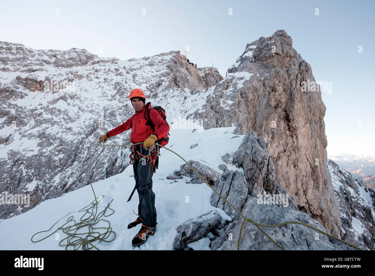 Mountain guide adjusting rope on cliff in mountain range Stock Photo