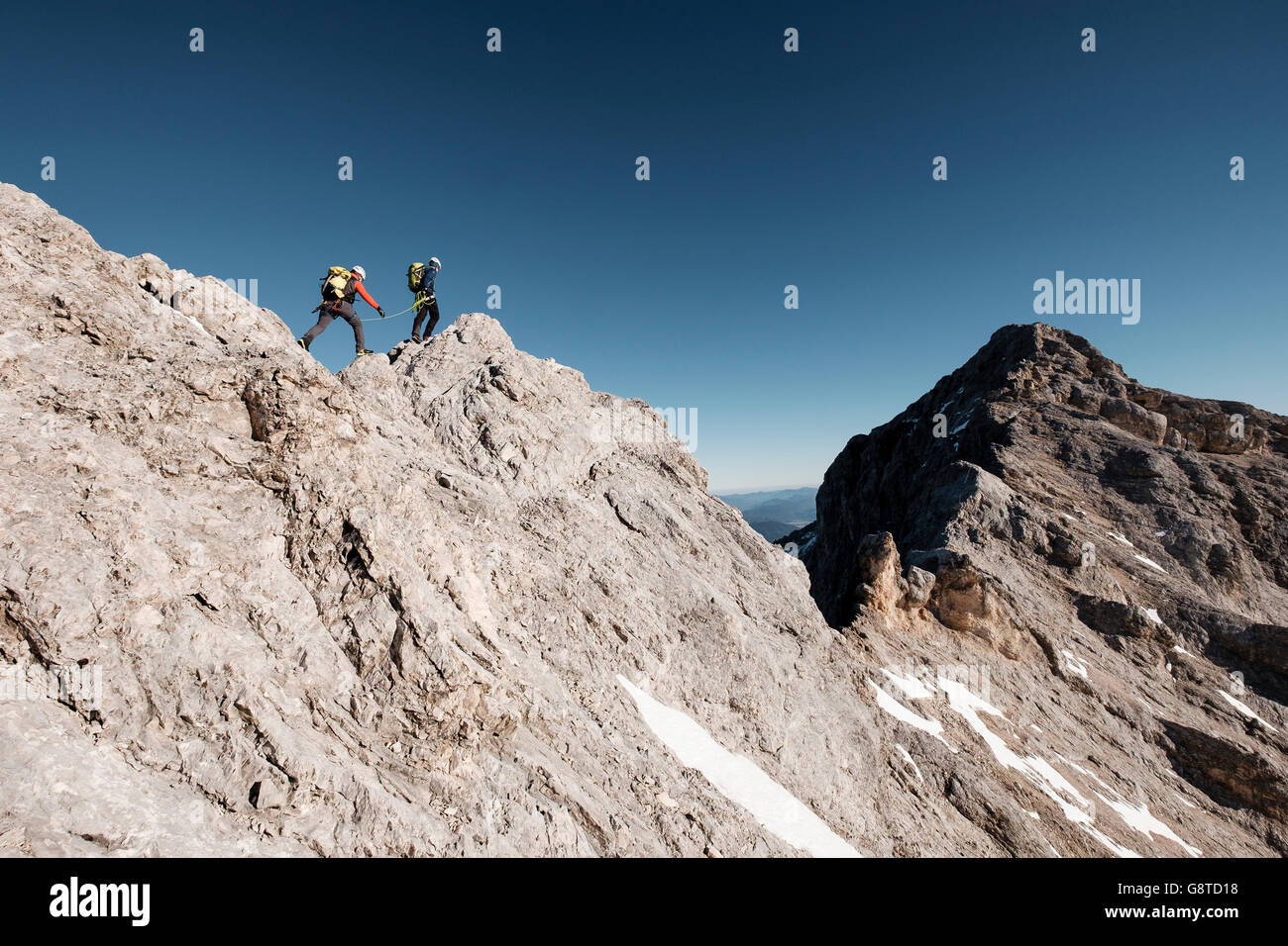 Two mountaineers hiking on mountain peak in European Alps Stock Photo