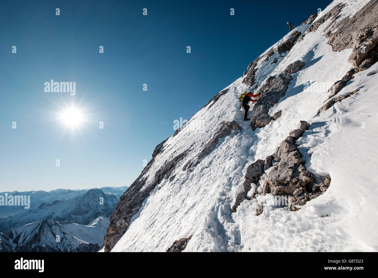 Two mountaineers climbing a snowcapped wall in European Alps Stock Photo
