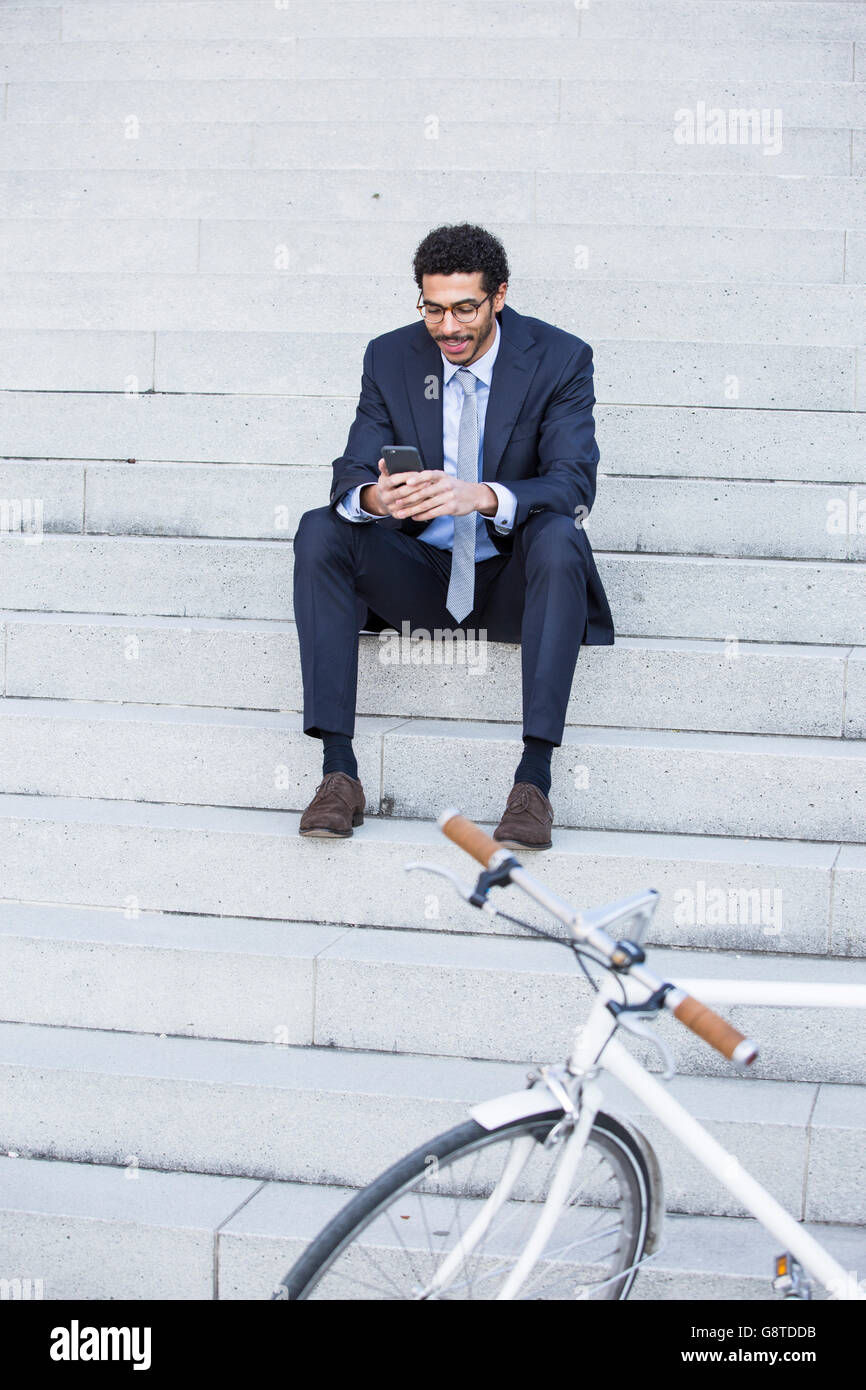 Businessman with bicycle using smart phone in city Stock Photo