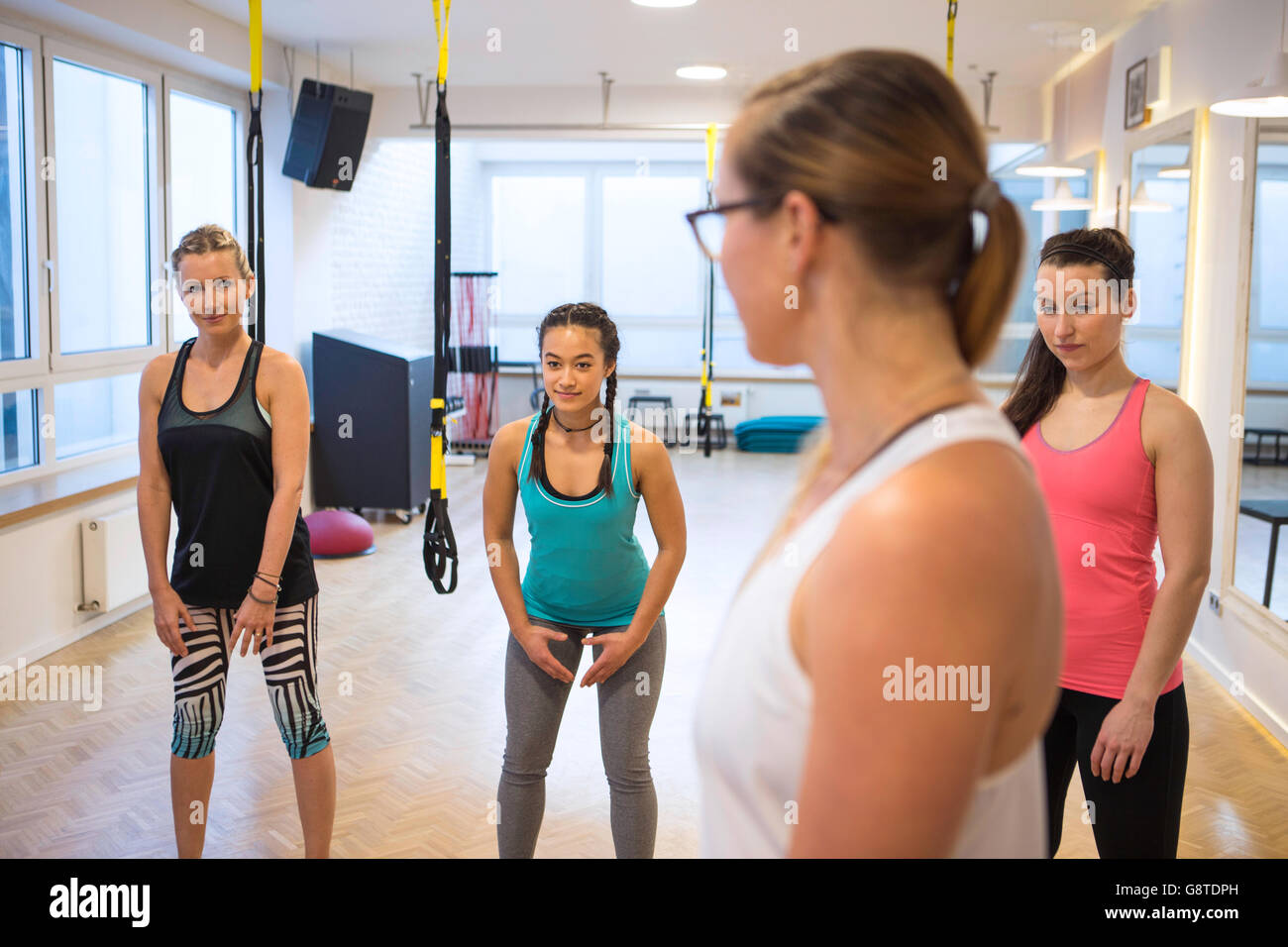 Fitness instructor teaches women how to perform suspension exercises Stock Photo