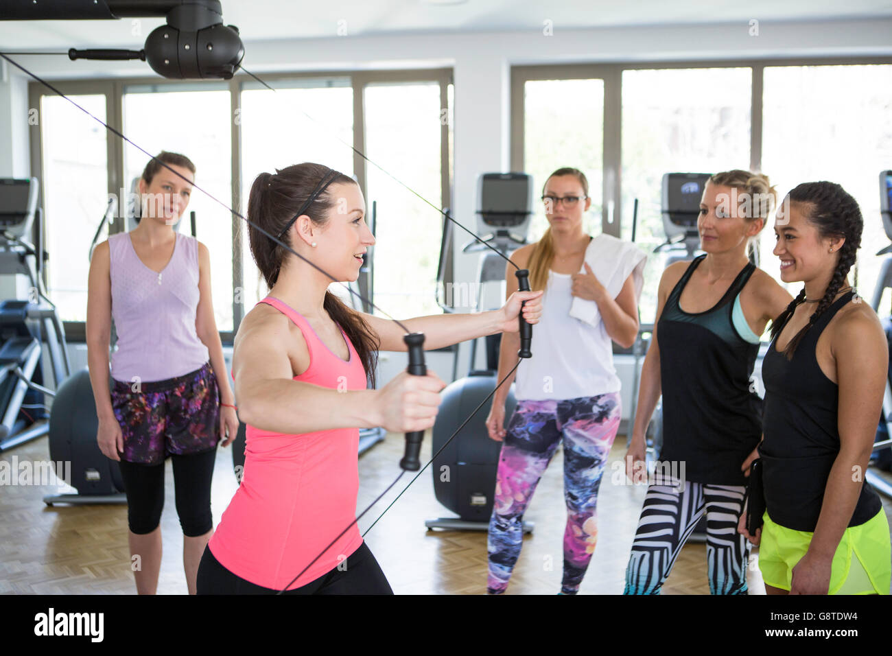 Fitness instructor shows women how to perform a suspension exercise Stock Photo
