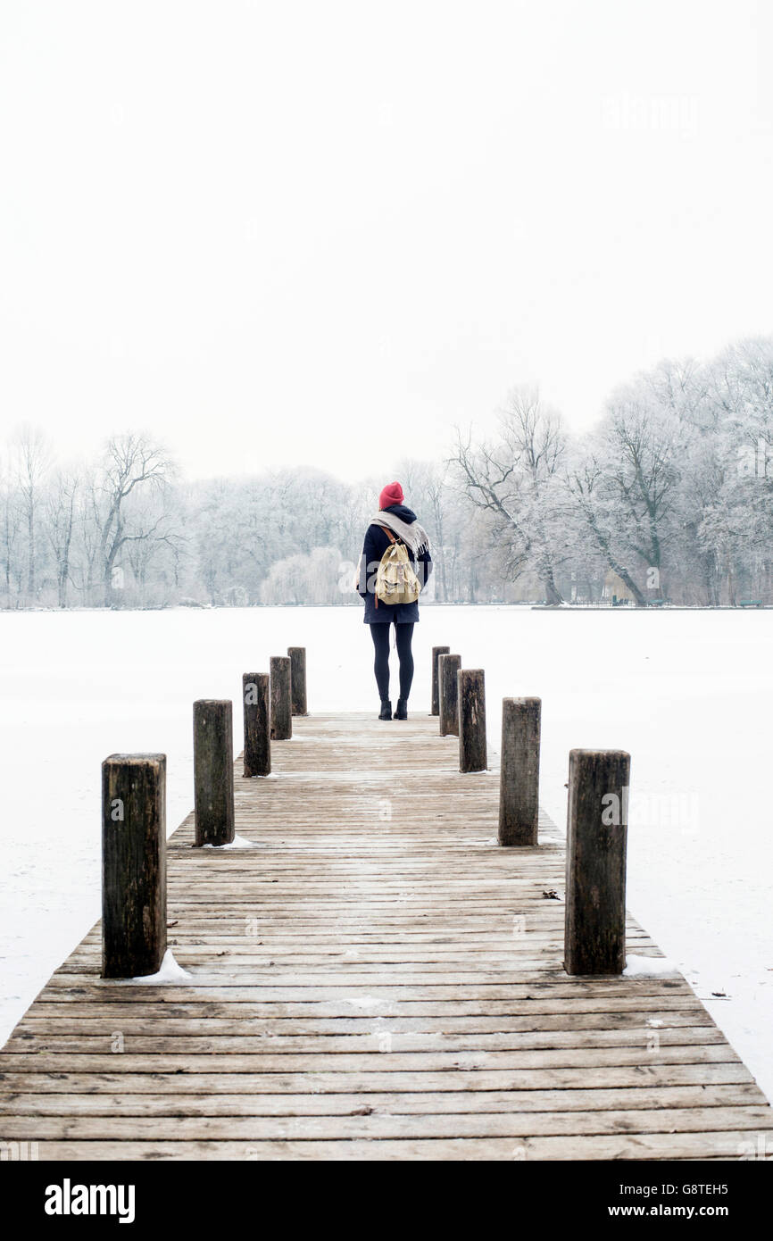 Mid adult woman on jetty looking at view in winter Stock Photo