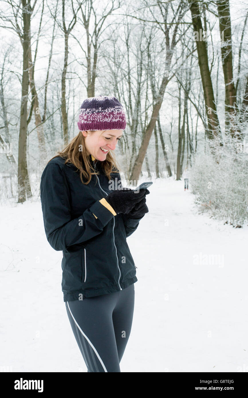 Mid adult woman with knit hat using smart phone in winter Stock Photo