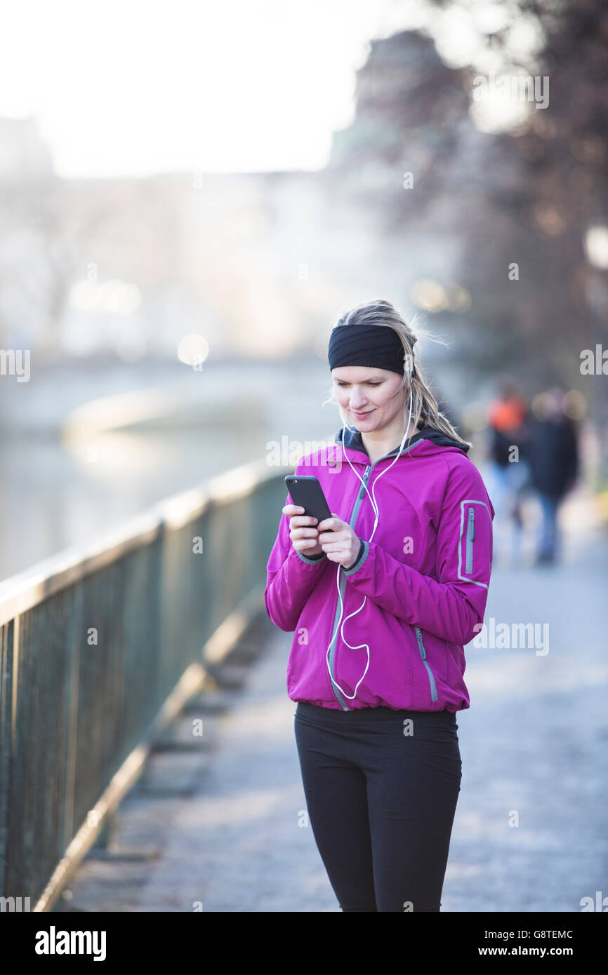 Woman in sports clothes using MP3 player in city Stock Photo