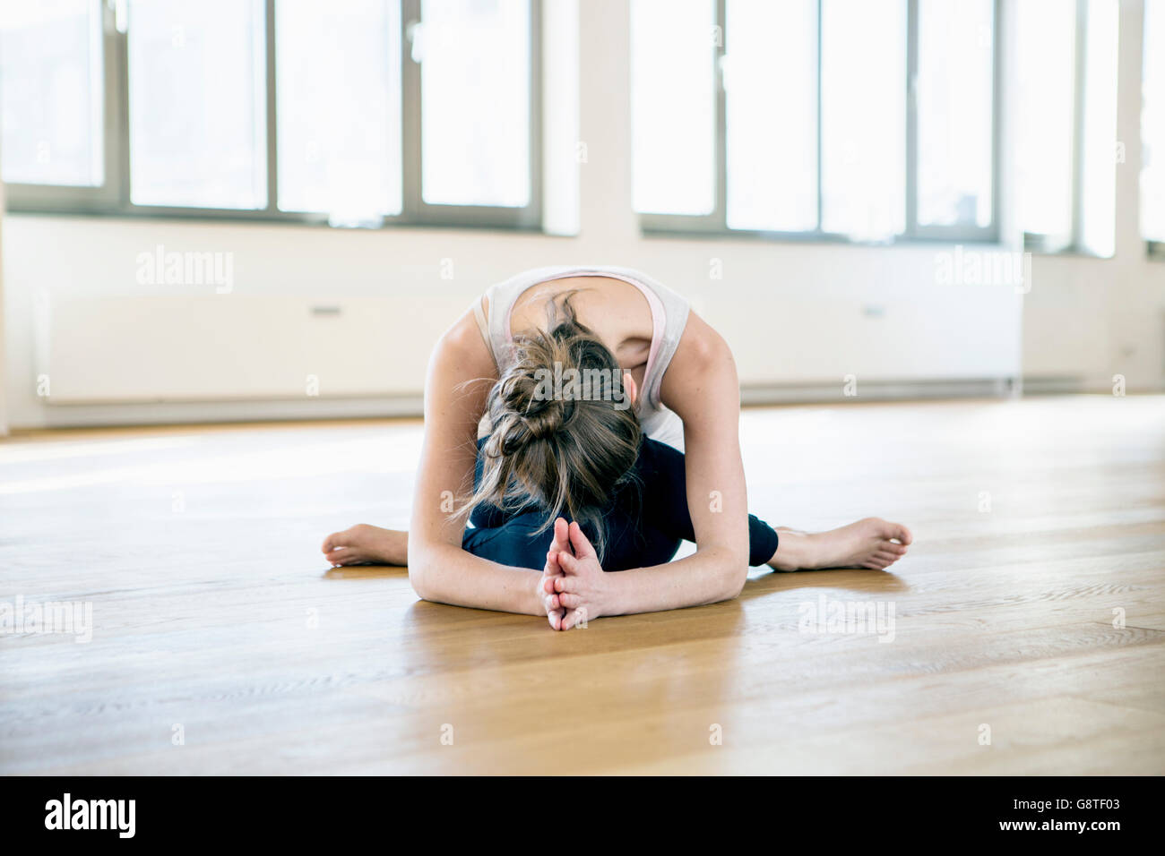 Woman sits in yoga pose bending over Stock Photo