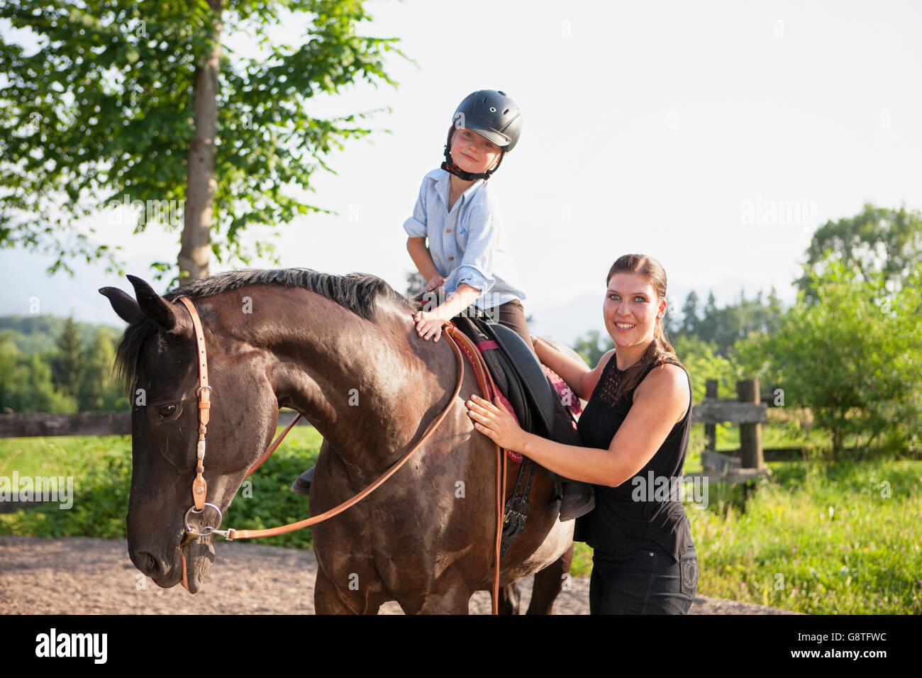 Girl learns to ride a horse with help of female instructor Stock Photo