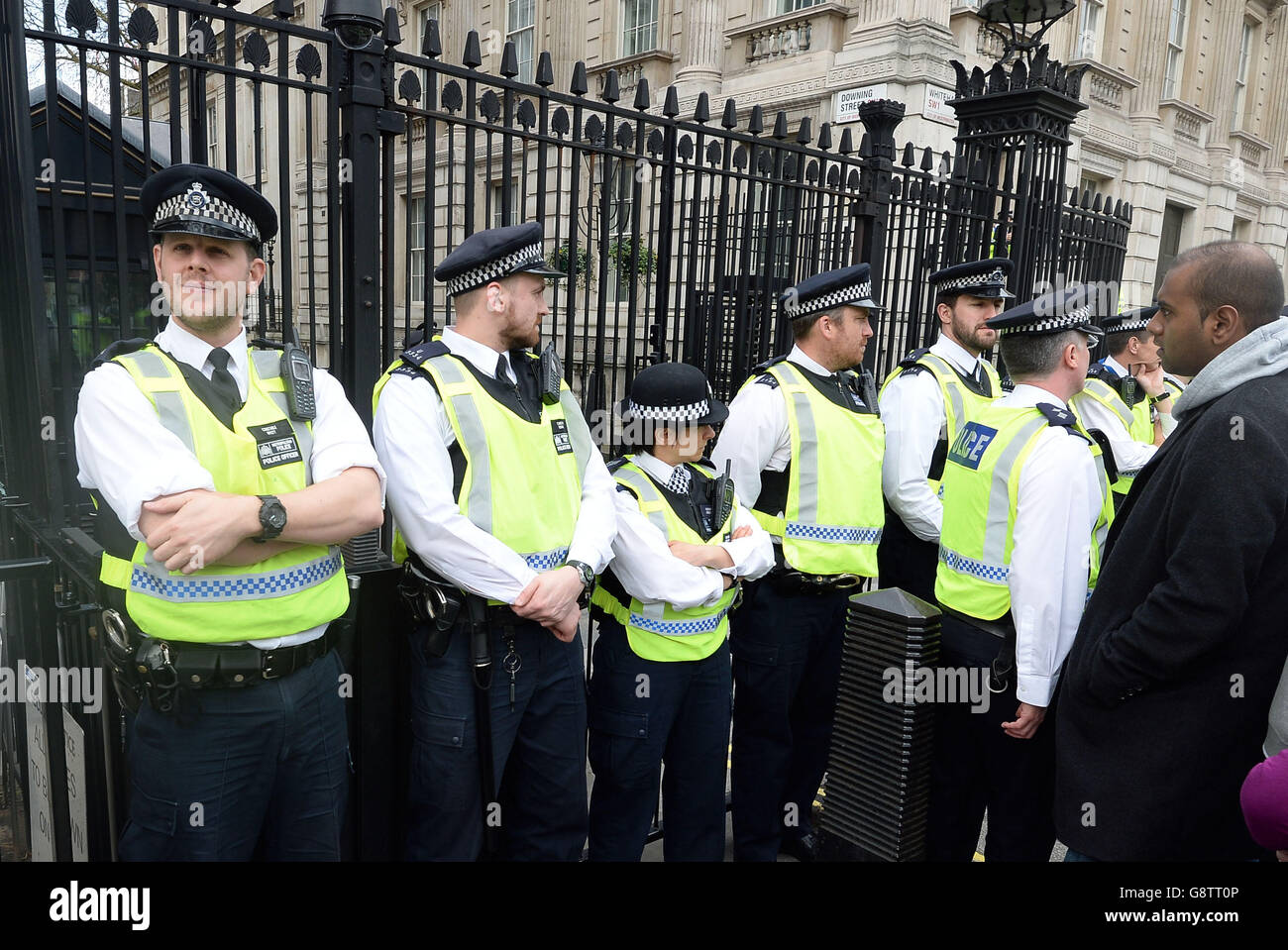 Police officers stand outside the gates of Downing Street in London as protesters gather to call for the resignation of Prime Minister David Cameron in the wake of the Mossack Fonseca data leak. Stock Photo