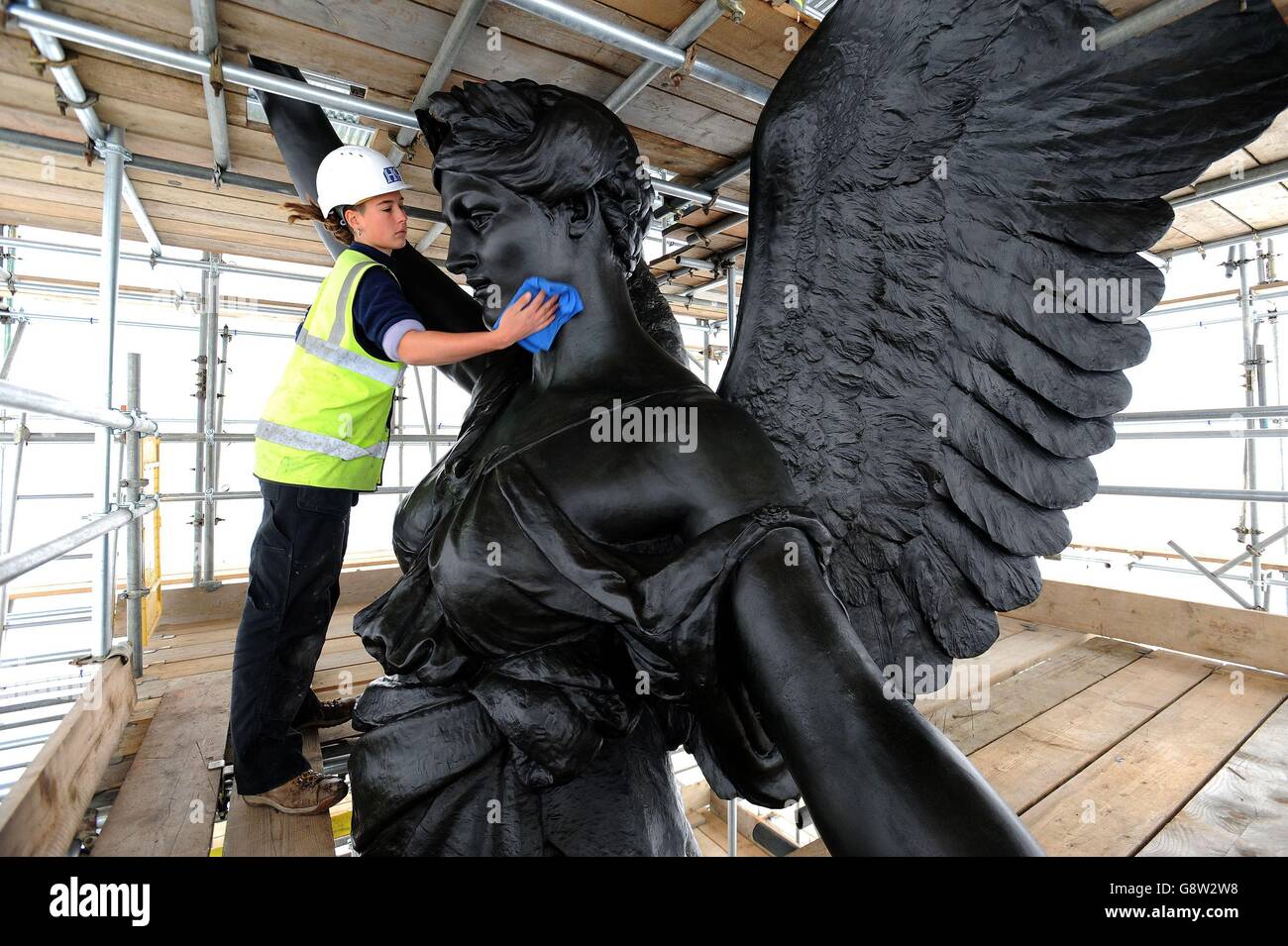 Freelance sculpture conservator Scarlett Hutchin, working for English Heritage, buffs wax polish applied to artist Adrian Jones' sculpture, Quadriga, on top of Wellington Arch at Hyde Park Corner, depicting four horses, representing the forces of chaos and war pulling a chariot, being calmed by the angel of peace, as the landmark sculpture is being cleaned, repaired and re-waxed by a team of specialists as part of a major English Heritage conservation programme. Stock Photo