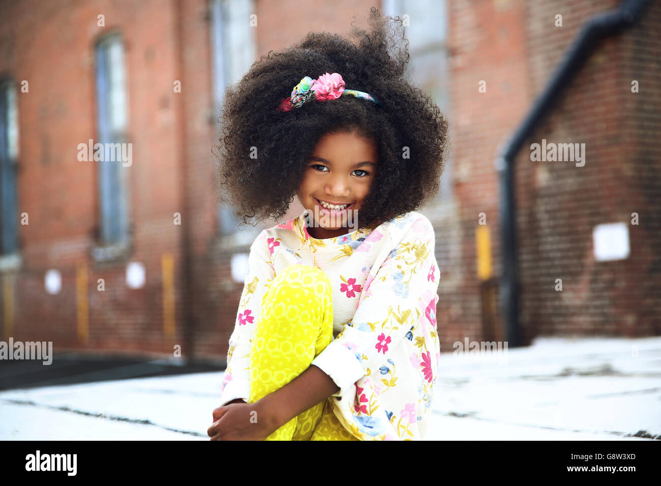 little girl poses for camera with an urban background Stock Photo