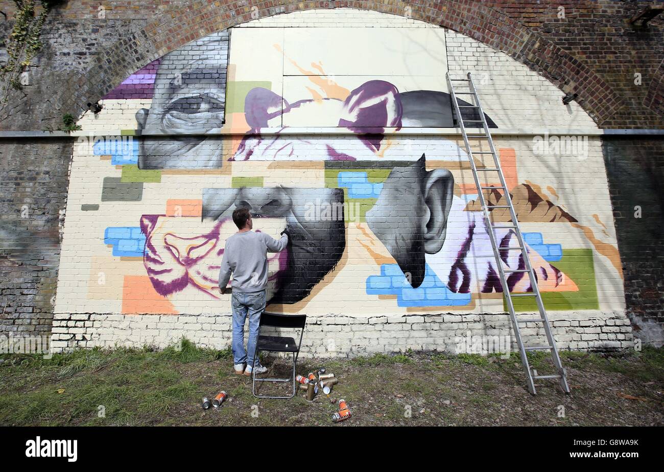 Mural artist Will Vibes spray paints against part of a 120 metre stretch of railway arches in Ackroyd Drive, Tower Hamlets, where several muralists have been invited to contribute to an art project called 'Endangered 13'. Stock Photo