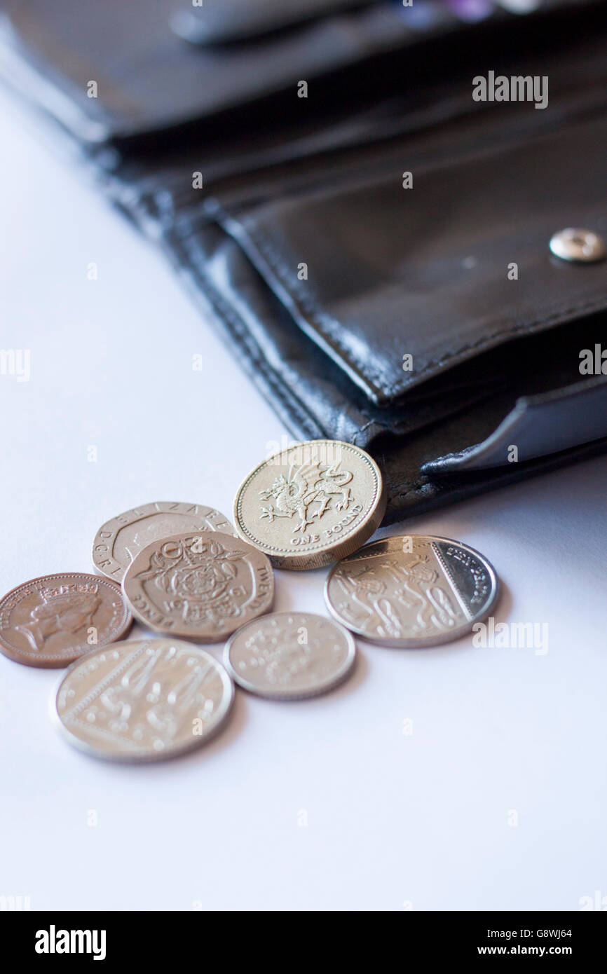 British pound coins spilling out from open black leather wallet Stock Photo Alamy