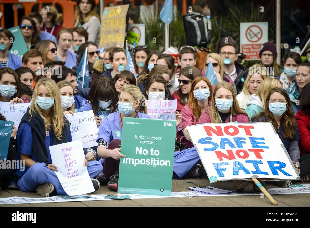 Junior doctors wear scrubs and masks as they sit down in a silent protest outside Bristol Royal Infirmary on the second day of all-out strike action during which they will provide no emergency care for patients. Stock Photo
