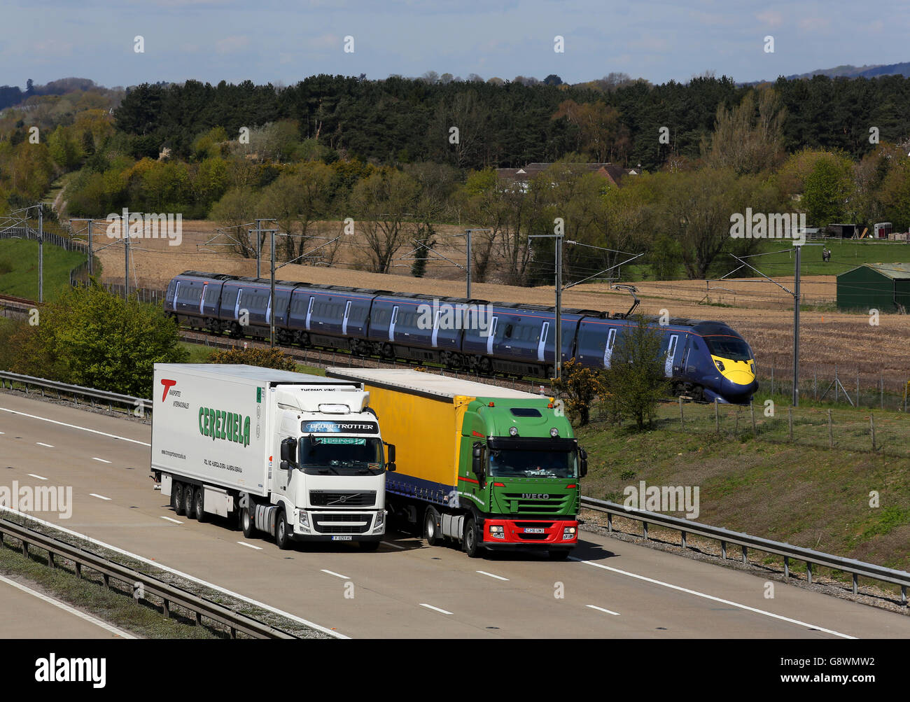 A high speed Javelin train using the HS1 railway line passes freight traffic on the M20 near