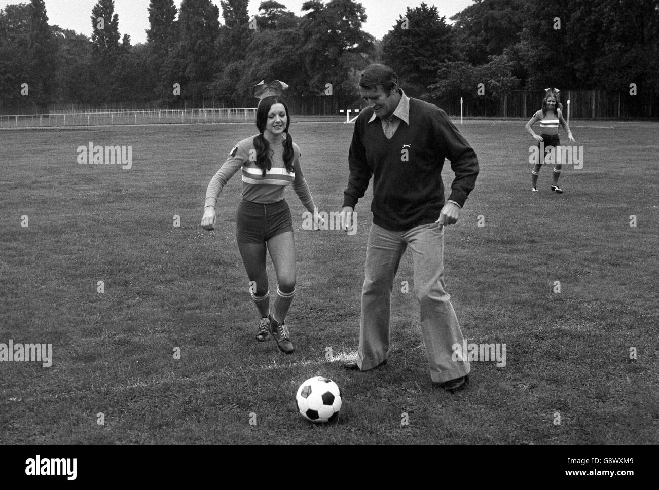 Crystal Palace FC manager Malcolm Allison shows a team of Playboy Club bunnies some skills before a match against a team of 'Apes' from the film Battle for the Planet of the Apes. The match was in aid of the World Wildlife Fund. Stock Photo