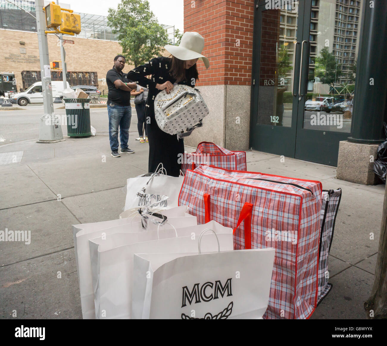A shopper with her MCM purchases outside of their sample sale in Soho in New York on Thursday, June 23, 2016. The German company, founded in 1976 sells luxury priced leather goods and was acquired by the Korea-based Sungjoo Group in 2005 which revitalized the brand. (© Richard B. Levine) Stock Photo