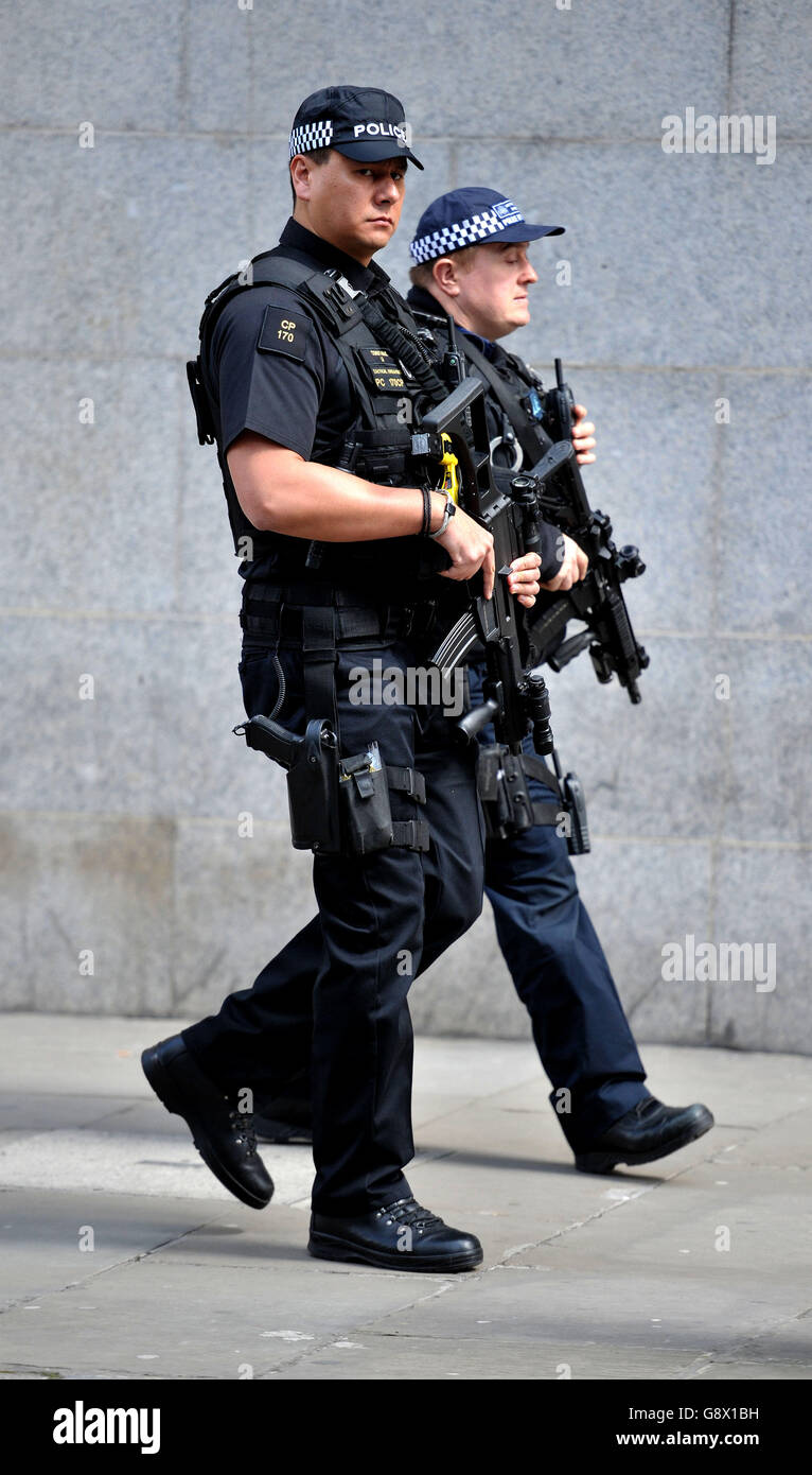 A Tactical Firearms officer from the City of London Police (left) and the Specialist Crime and Operations Specialist Firearms Command (SCO19) of the Metropolitan Police (right) patrol outside the Old Bailey. Stock Photo