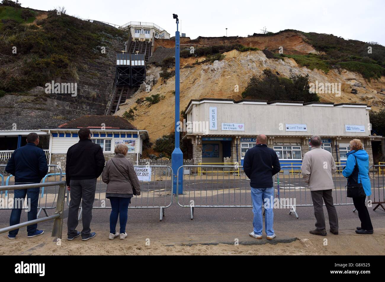 Members of the public look up at the collapsed cliff next to the East Cliff funicular railway on Bournemouth Beach, which has been damaged after a huge landslide saw tonnes of debris crash down on a coastal resort. Stock Photo