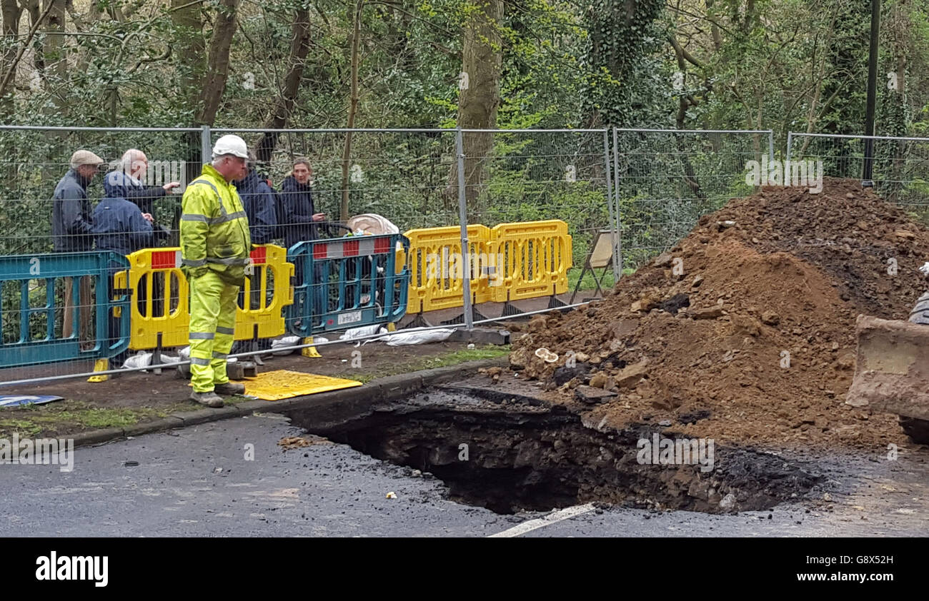 Members of the public look on as work is carried out on a sinkhole more than 20ft deep which appeared on Hutcliffe Wood Road in Sheffield, which links the city suburbs of Woodseats and Millhouses. Stock Photo