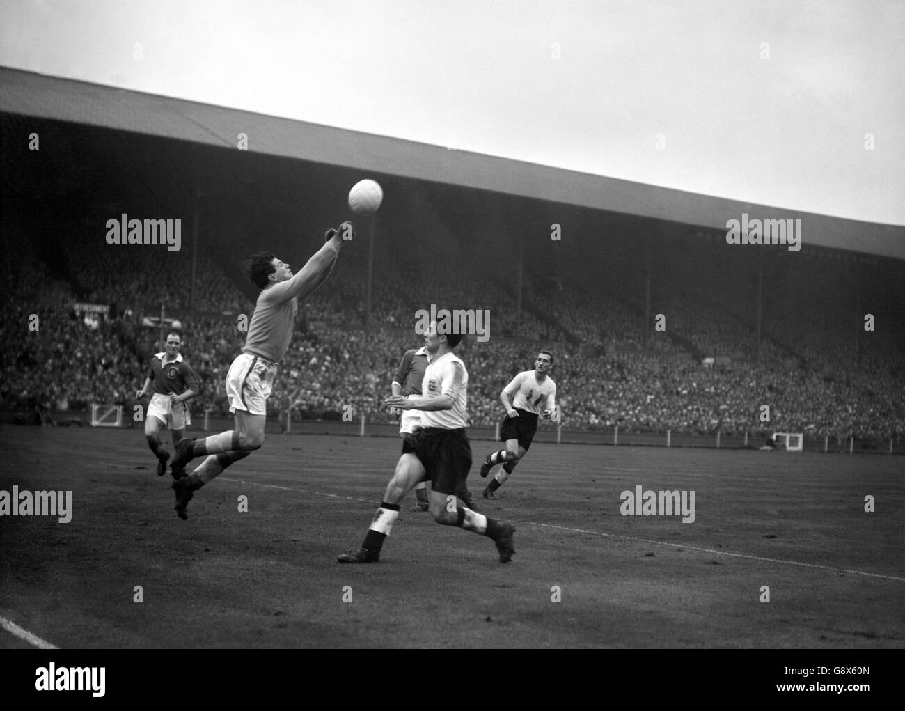 John King, goalkeeper for Wales, saves as England's Ronnie Allen rushes