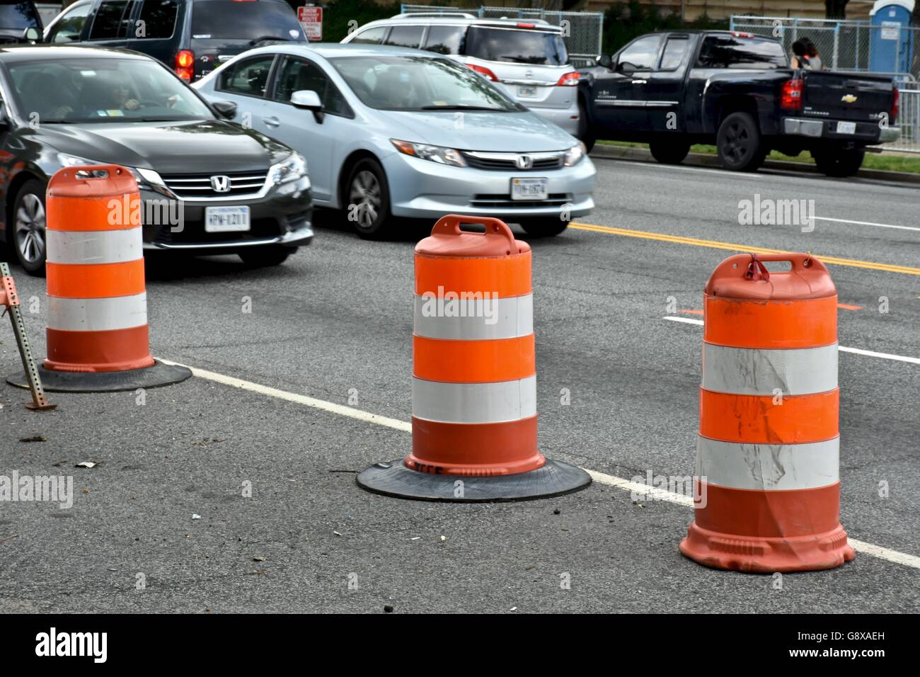 Three traffic cones on the side of a busy street in Washington DC Stock