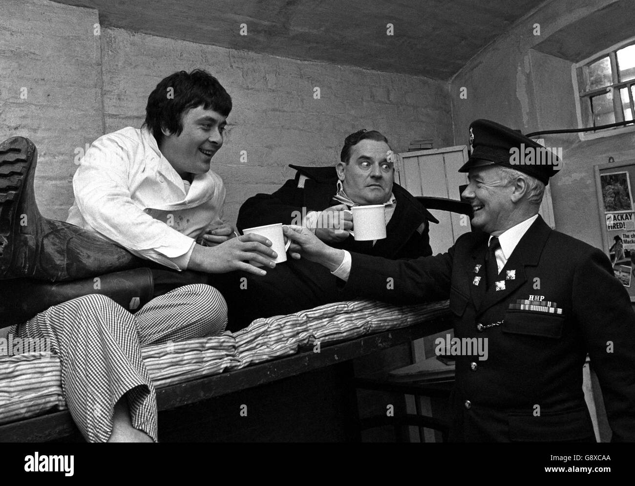 Habitual prisoner Norman Stanley Fletcher, alias actor Ronnie Barker (centre), is highly suspicious of the motives of a prison officer portrayed by actor Fulton Mackay, offering a mug of tea to cell-mate Richard Beckinsale at Chelmsford Prison. Stock Photo