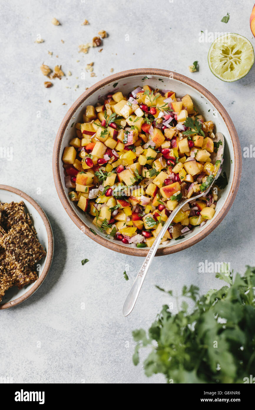 A bowl of peach and walnut salsa served with some crackers in photographed from the top view. Stock Photo