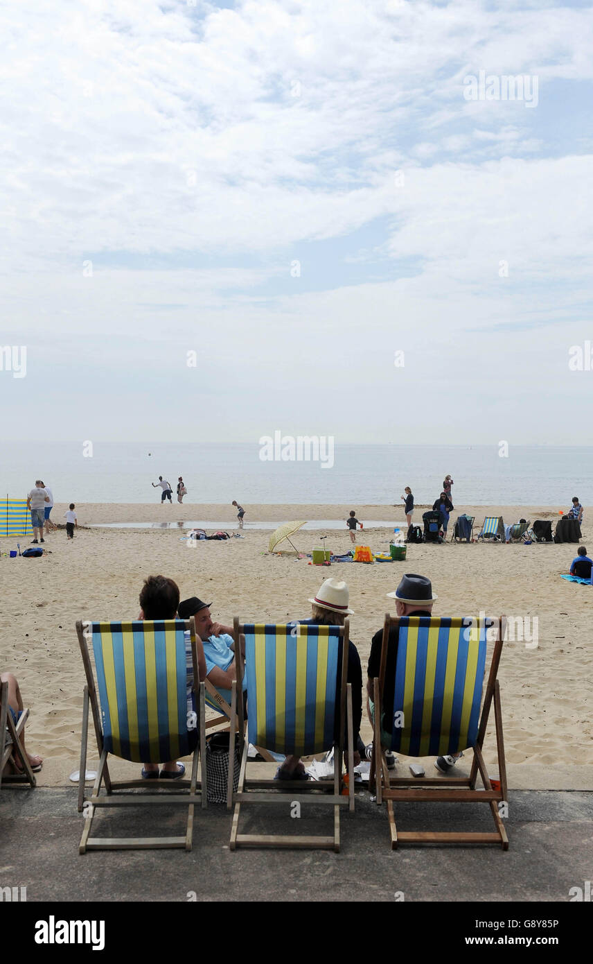 People sitting in deck chairs enjoy the warm weather on Bournemouth
