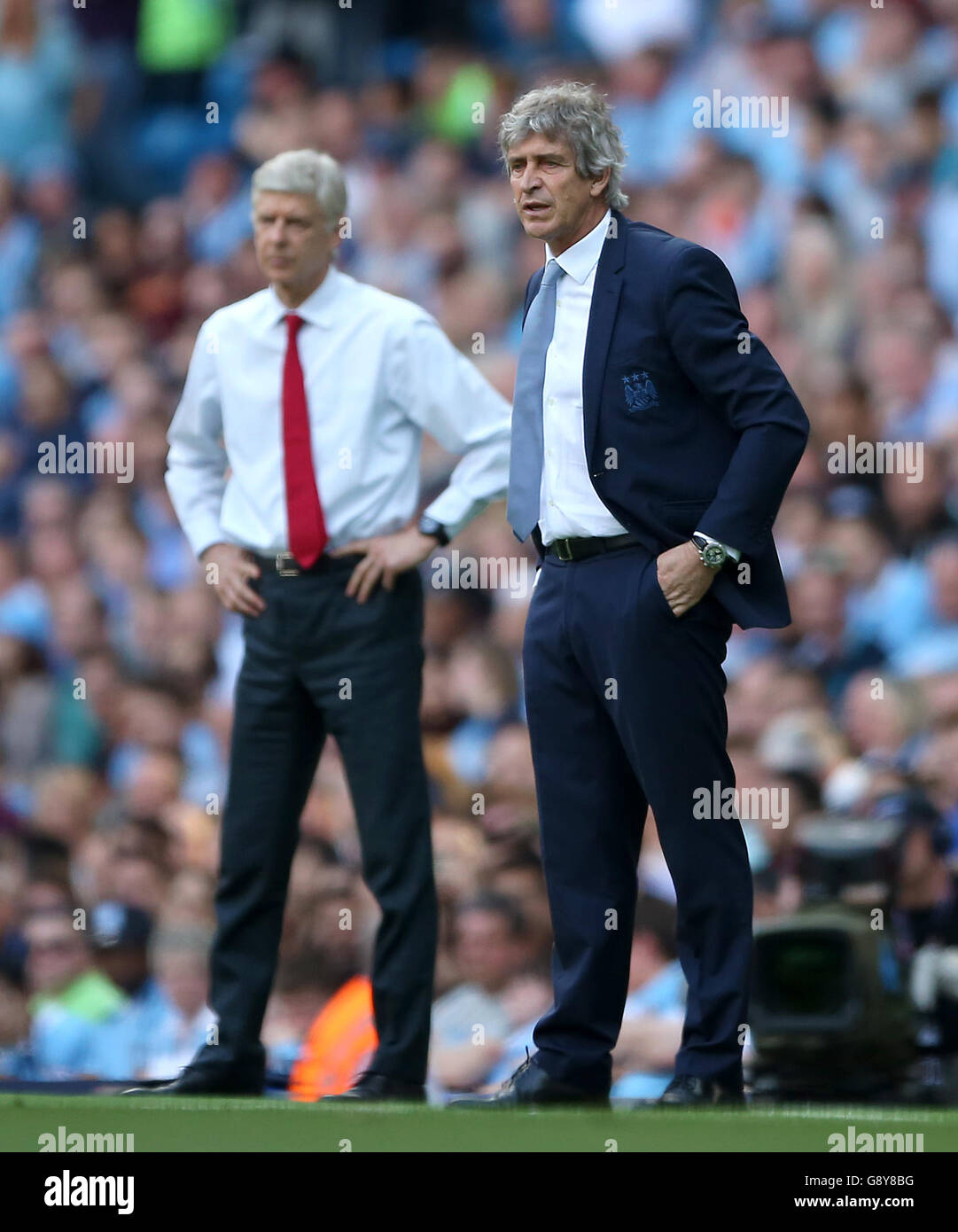 Manchester City manager Manuel Pellegrini (right) with Arsenal manager Arsene Wenger on the touchline during the Barclays Premier League match at the Etihad Stadium, Manchester. Stock Photo