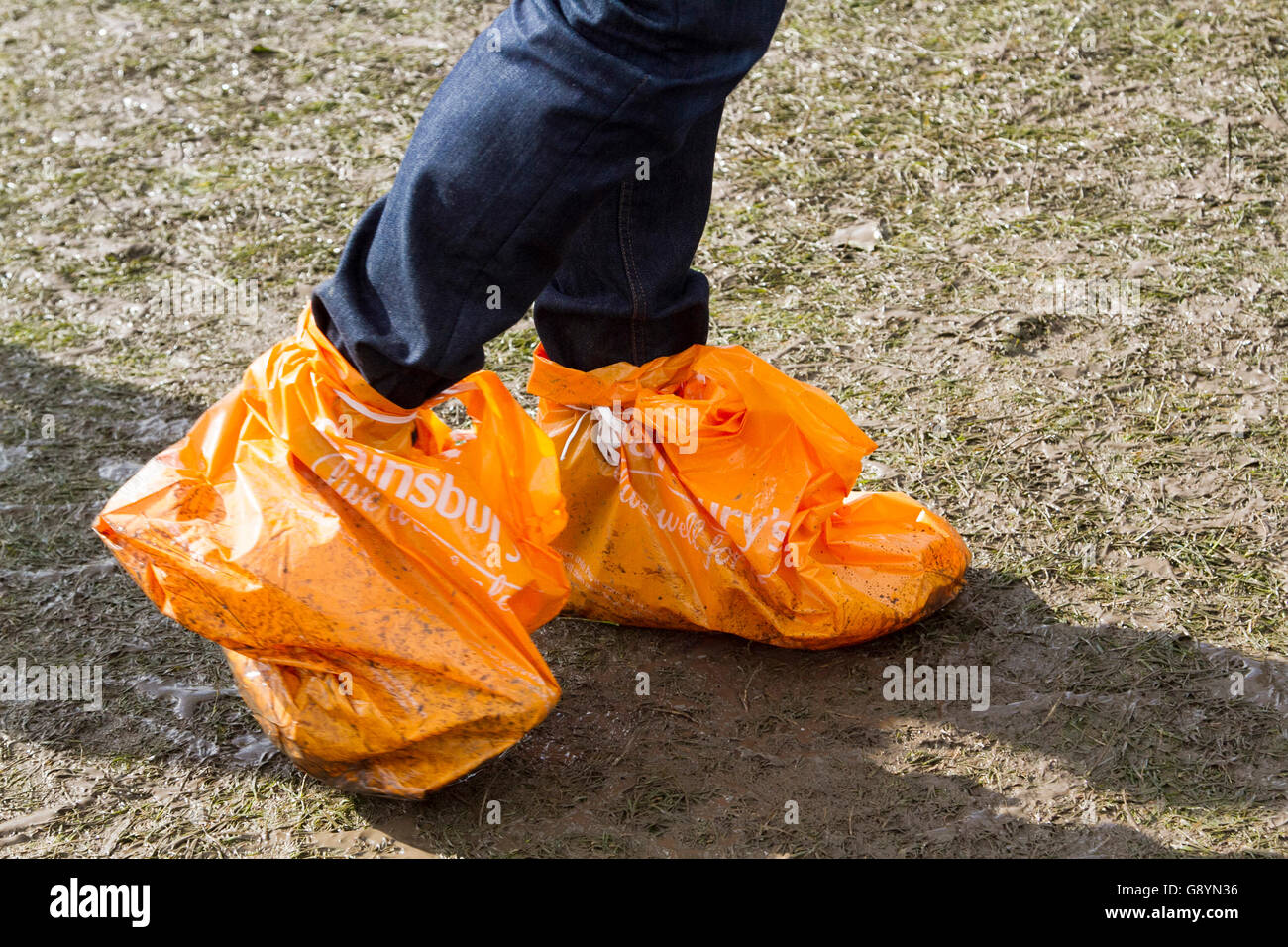 Wimbledon London,UK. 30th June 2016. A Tennis fan with feet wrapped in  plastic bags walks on muddy surface in Wimbledon Park following the rains  on Day 4 of the 2016 Wimbledon Championships